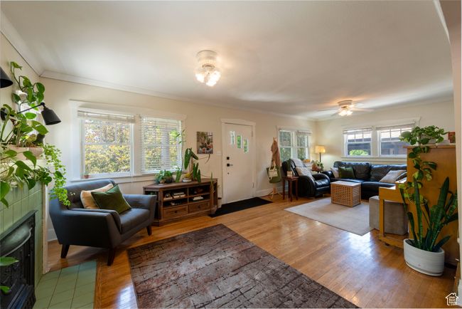 Living area with wood finished floors, a tiled fireplace, crown molding, and ceiling fan | Image 7