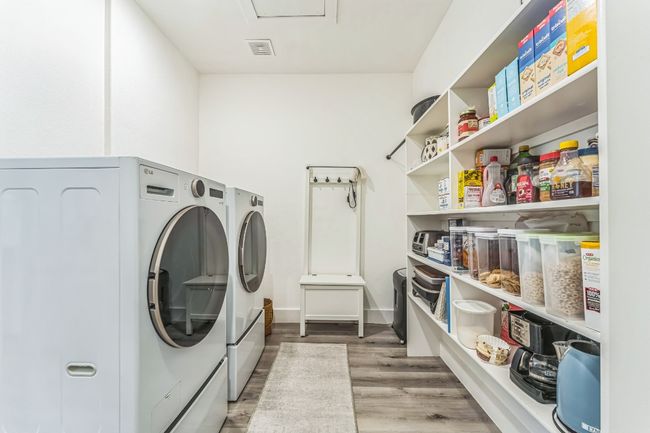 Laundry room with washing machine and dryer and wood finished floors. | Image 23