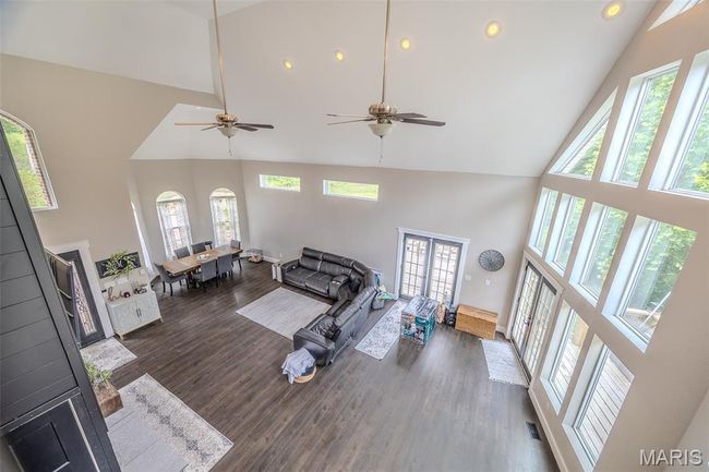 Living room with high vaulted ceiling, recessed lighting, wood finished floors, and a ceiling fan | Image 37