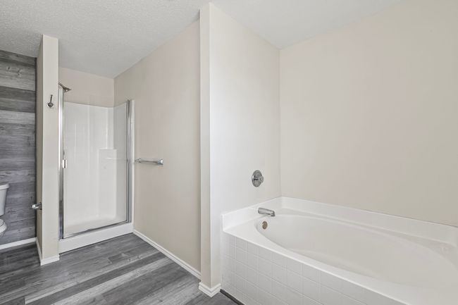 Full bathroom with a bath, a shower, wood finished floors, and a textured ceiling | Image 20