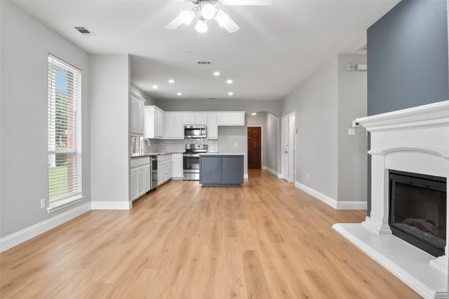 Kitchen featuring appliances with stainless steel finishes, a ceiling fan, arched walkways, decorative backsplash, and white cabinets | Image 9