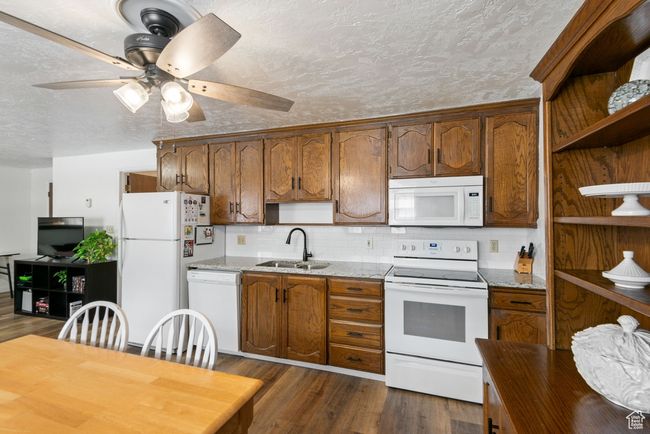 Kitchen featuring white appliances, open shelves, dark wood-style floors, a ceiling fan, and tasteful backsplash | Image 6