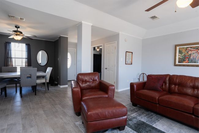Living area featuring ceiling fan, baseboards, wood finished floors, and crown molding | Image 7