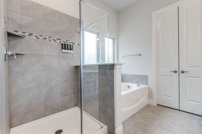 Bathroom with a tile shower, tile patterned flooring, and a bath | Image 21