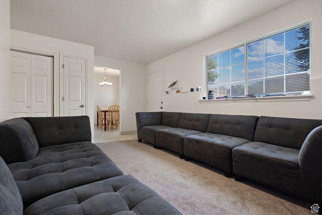 Carpeted living area featuring a chandelier and baseboards | Image 23