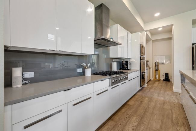 Kitchen with wall chimney exhaust hood, modern cabinets, stainless steel appliances, and recessed lighting | Image 12