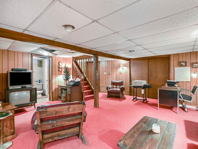 Carpeted living room featuring a paneled ceiling and wood walls | Image 30