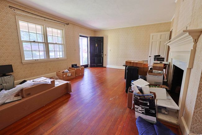 Home office with dark wood finished floors, wallpapered walls, and a fireplace | Image 4
