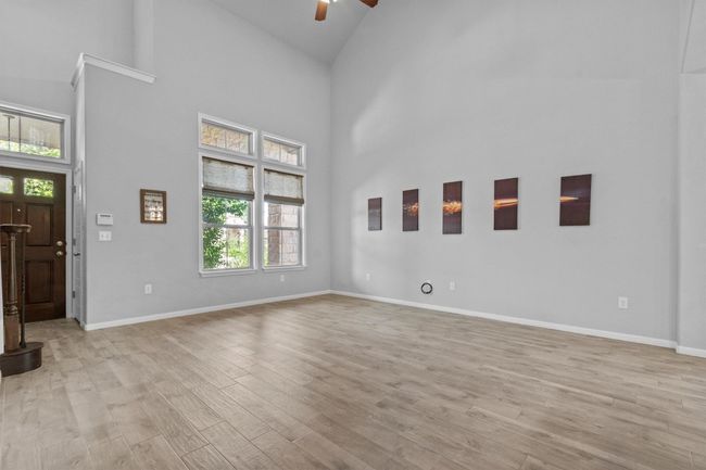 Unfurnished living room with ceiling fan, healthy amount of natural light, high vaulted ceiling, and light wood-style floors | Image 11