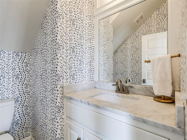 Half bath with lofted ceiling, toilet, tile walls, vanity, and visible vents | Image 12