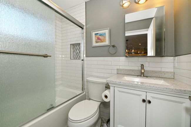 Full bathroom with tile walls, vanity, enclosed tub / shower combo, and toilet | Image 27
