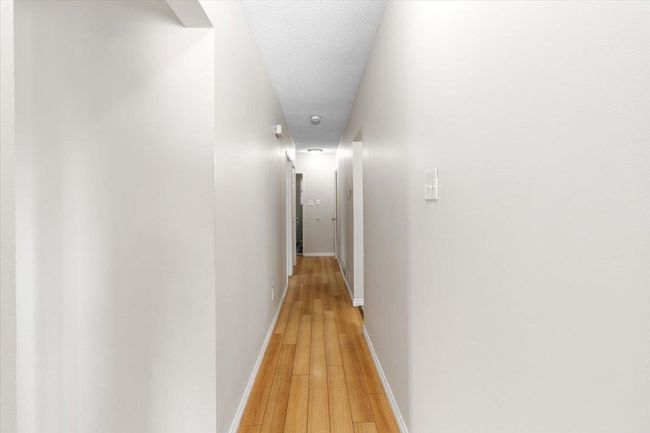 Hall featuring light wood-style flooring, a textured ceiling, and baseboards | Image 17