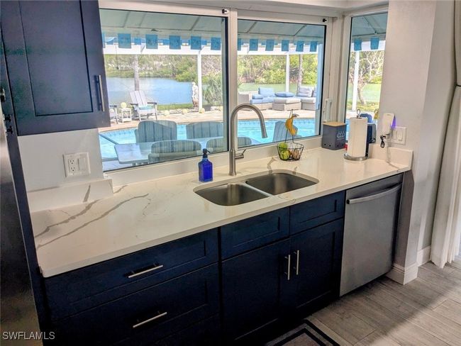 Kitchen featuring a sink, blue cabinets, dishwasher, light wood-style flooring, and a water view | Image 19