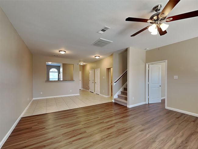 Empty room featuring light wood-style flooring, stairs, and ceiling fan | Image 4
