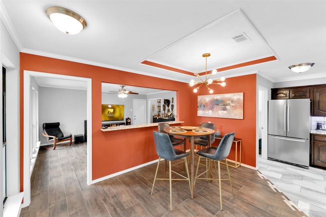 Dining room with ornamental molding, a raised ceiling, a chandelier, and light wood-style flooring | Image 16