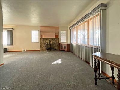 Unfurnished living room with a healthy amount of sunlight, light colored carpet, and a fireplace | Image 3