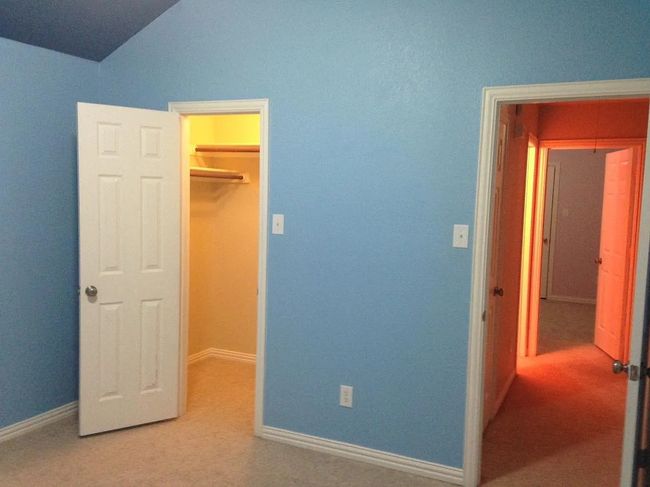 Unfurnished bedroom with a spacious closet, carpet flooring, and lofted ceiling | Image 15