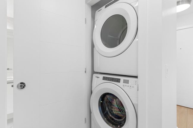 Laundry room featuring stacked washer / drying machine and wood finished floors | Image 18