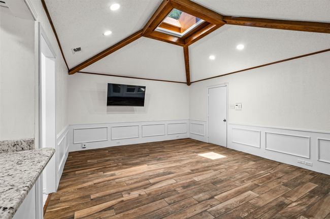 Unfurnished living room featuring vaulted ceiling, wainscoting, recessed lighting, dark wood-type flooring, and a decorative wall | Image 10