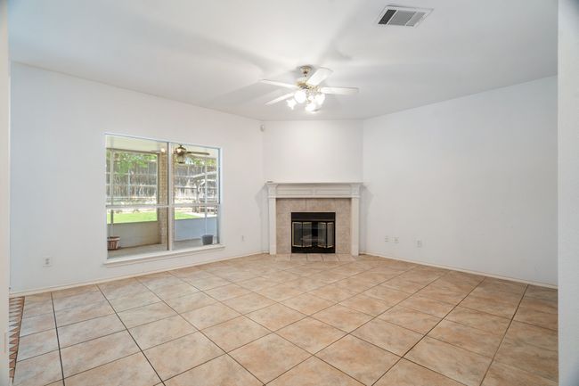 Unfurnished living room featuring a tiled fireplace, visible vents, ceiling fan, and tile patterned flooring | Image 16