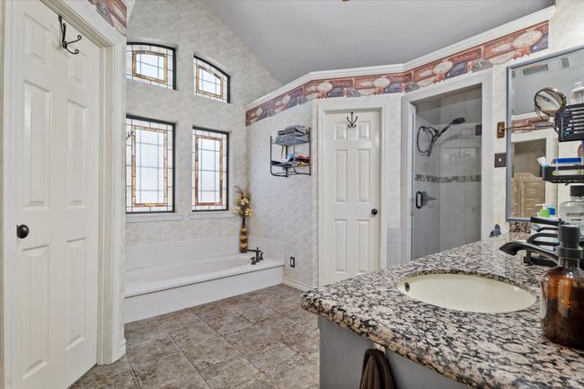 Bathroom featuring healthy amount of natural light, a bath, a stall shower, vanity, and vaulted ceiling | Image 22