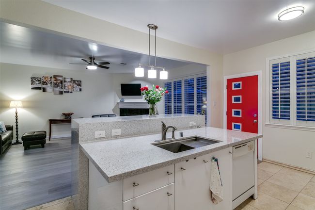Kitchen with white dishwasher, a sink, open floor plan, and decorative light fixtures | Image 12