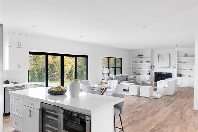 Kitchen featuring light wood-type flooring, beverage cooler, white cabinets, and a kitchen bar | Image 6