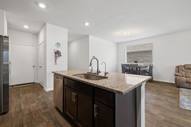 Kitchen featuring a sink, stainless steel appliances, light stone counters, dark wood-style floors, and baseboards | Image 13