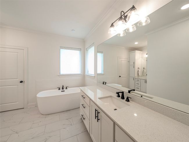 Full bath featuring a freestanding tub, vanity, ornamental molding, marble finish flooring, and a chandelier | Image 24