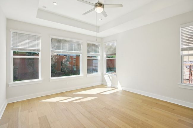 Unfurnished room with a tray ceiling, light wood-type flooring, and ceiling fan | Image 9