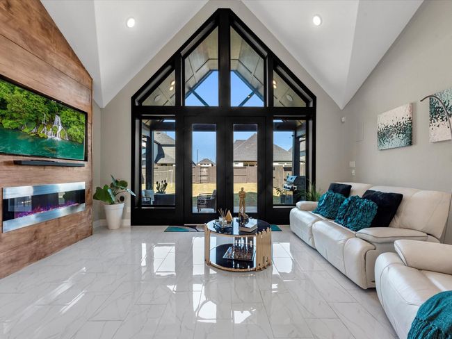 Step into this family room with a stunning, modern aesthetic with high vaulted ceiling and large triangular windows that bring natural light. this space I prefect for relaxation with the family and entertaining! | Image 11