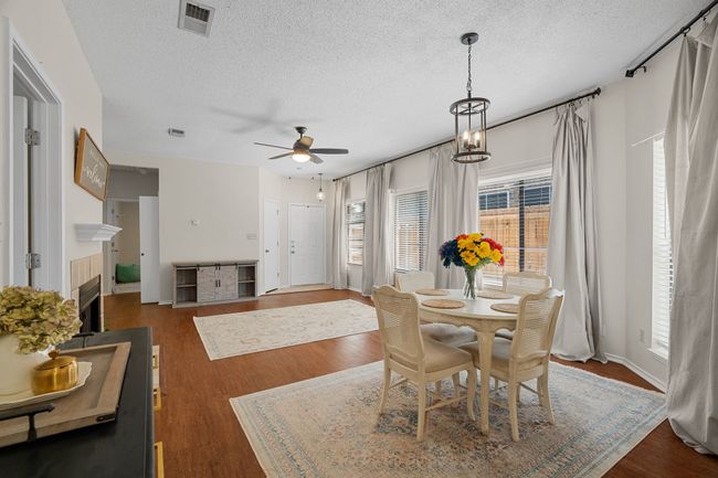 Dining room with a textured ceiling, ceiling fan, dark wood-style flooring, and a fireplace | Image 6