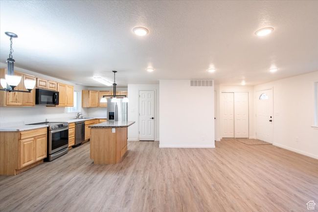 Kitchen with appliances with stainless steel finishes, a sink, light wood-style flooring, baseboards, and a kitchen island | Image 12