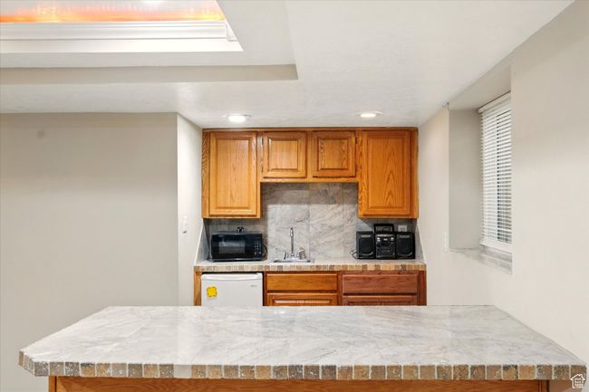 Kitchen with black microwave, dishwasher, tasteful backsplash, light countertops, and recessed lighting | Image 33