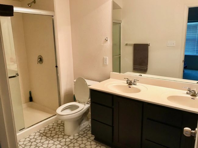 Full bathroom featuring double vanity, toilet, a shower stall, and a sink | Image 12