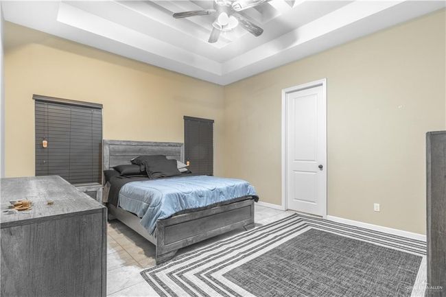 Tiled bedroom with ceiling fan and a raised ceiling | Image 13
