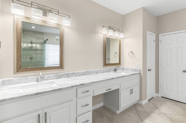 Bathroom with baseboards, double vanity, a sink, and a stall shower | Image 25