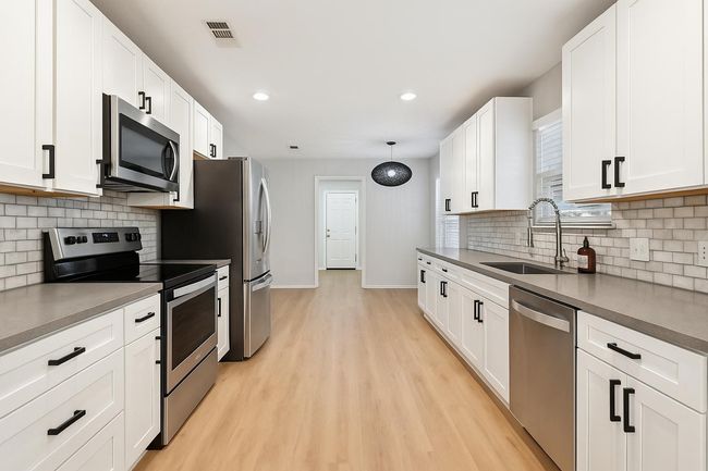 Kitchen featuring appliances with stainless steel finishes, a sink, baseboards, backsplash, and recessed lighting | Image 11