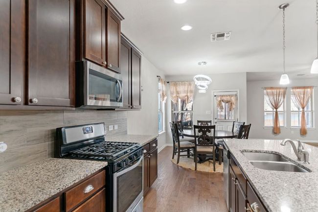 Kitchen featuring a sink, tasteful backsplash, wood finished floors, stainless steel appliances, and visible vents | Image 20