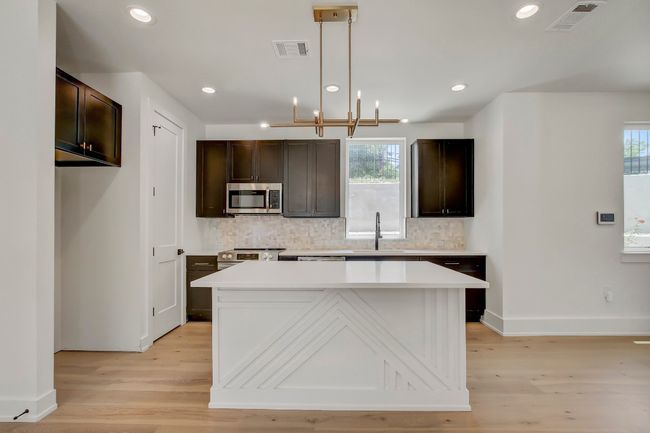Kitchen featuring appliances with stainless steel finishes, a sink, backsplash, light wood-style floors, and dark brown cabinets | Image 11