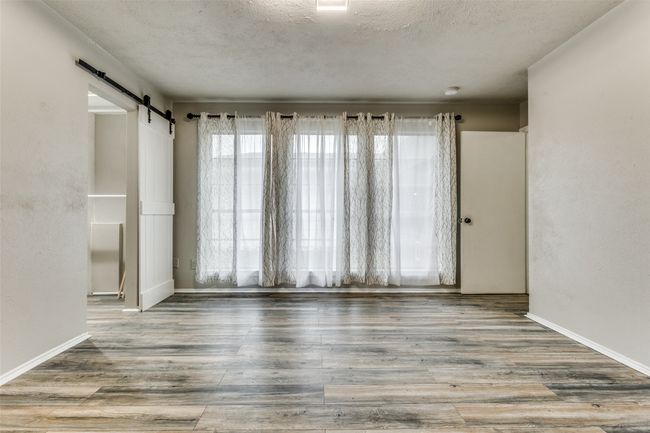 Unfurnished room featuring a textured ceiling, a barn door, and wood finished floors | Image 20