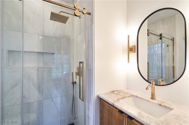 Bedroom 3's full bath newly remodeled with marble tiled shower, a new wall hanging cabinet and Cristallo Quartzife counter top and black tile flooring | Image 22