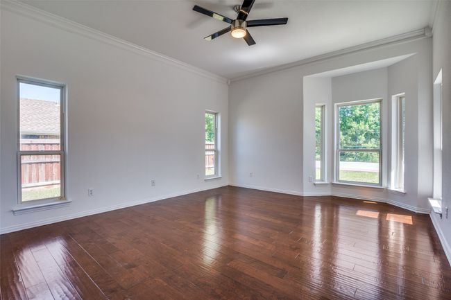 Empty room with crown molding, ceiling fan, dark wood-style flooring, and baseboards | Image 13