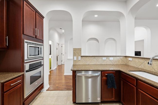 Kitchen with stainless steel appliances, dark brown cabinets, stone countertops, and recessed lighting | Image 15