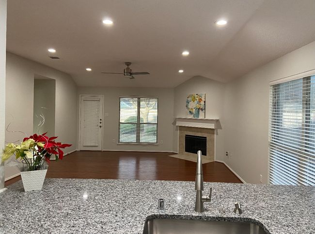 Kitchen with a ceiling fan, stone counters, recessed lighting, a fireplace, and wood finished floors | Image 7