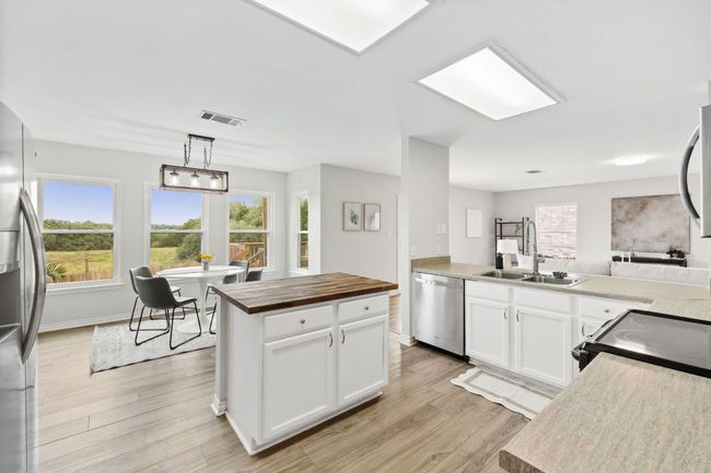 Kitchen featuring appliances with stainless steel finishes, butcher block counters, a sink, light wood-type flooring, and plenty of natural light | Image 17