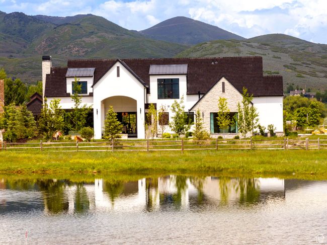 View of front facade with a chimney, stucco siding, stone siding, and a water and mountain view | Image 60