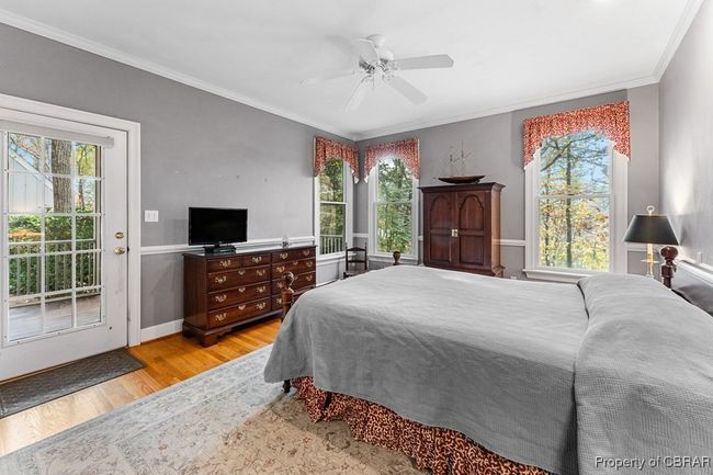 Bedroom featuring wood finished floors, crown molding, access to outside, multiple windows, and a ceiling fan | Image 26