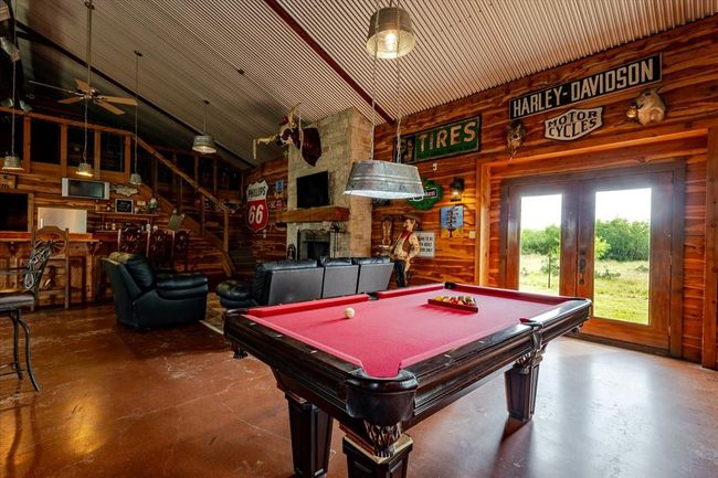 Playroom featuring wooden walls, a stone fireplace, finished concrete flooring, and billiards | Image 5
