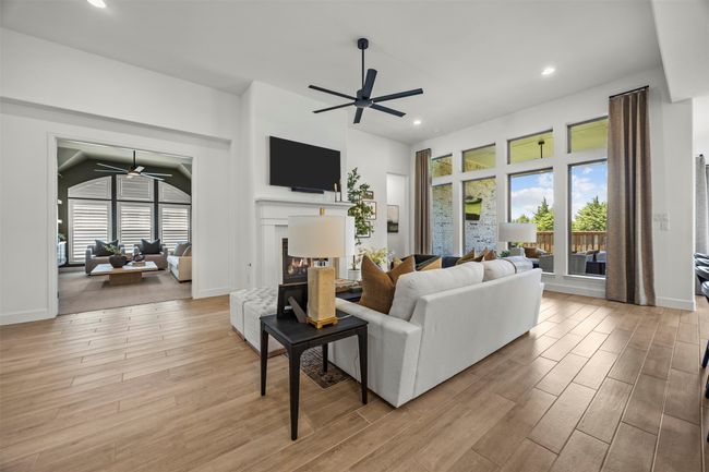 Living area featuring ceiling fan, a glass covered fireplace, plenty of natural light, light wood-style flooring, and recessed lighting | Image 15